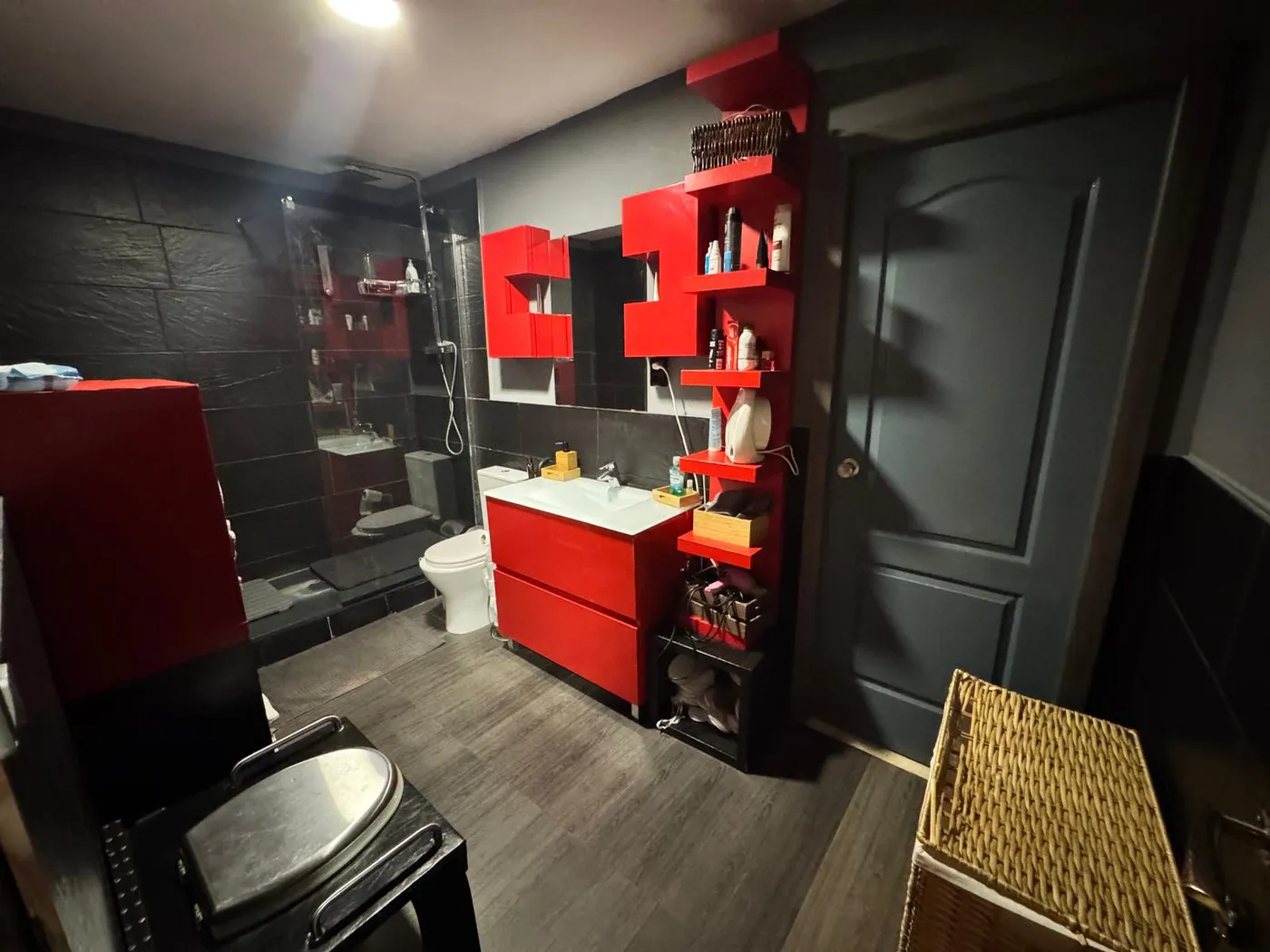 Baño privado con acabados rojo y negro, secador y toallas